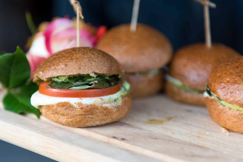Continental Catering caprese sliders on a wood board with a garden rose