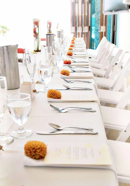 Continental Catering long white reception table set with menus and dahlia blooms