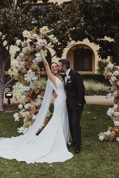 Events Inspired couple between tall floral pillars under a magnolia tree