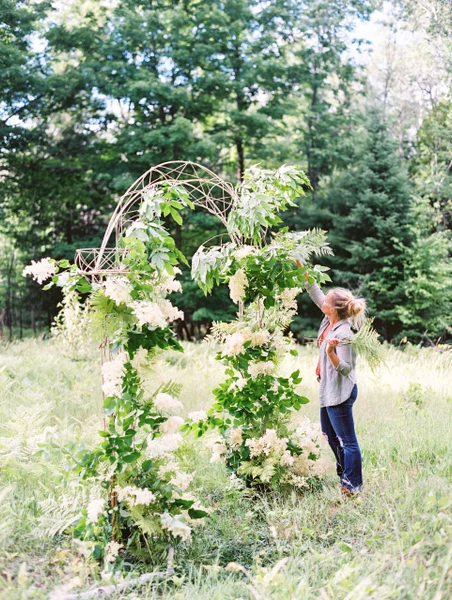 BLOOM floral design freestanding ceremony arch of white blooms and greenery in a woodland fern meadow