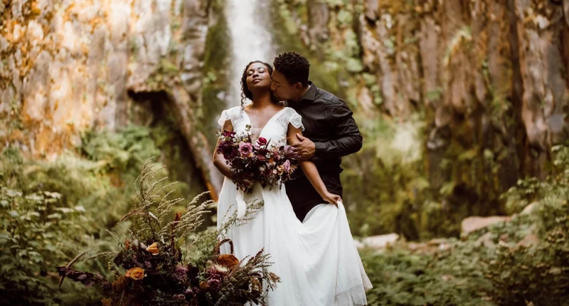 Khoa Photography couple embracing with a bouquet beside a waterfall