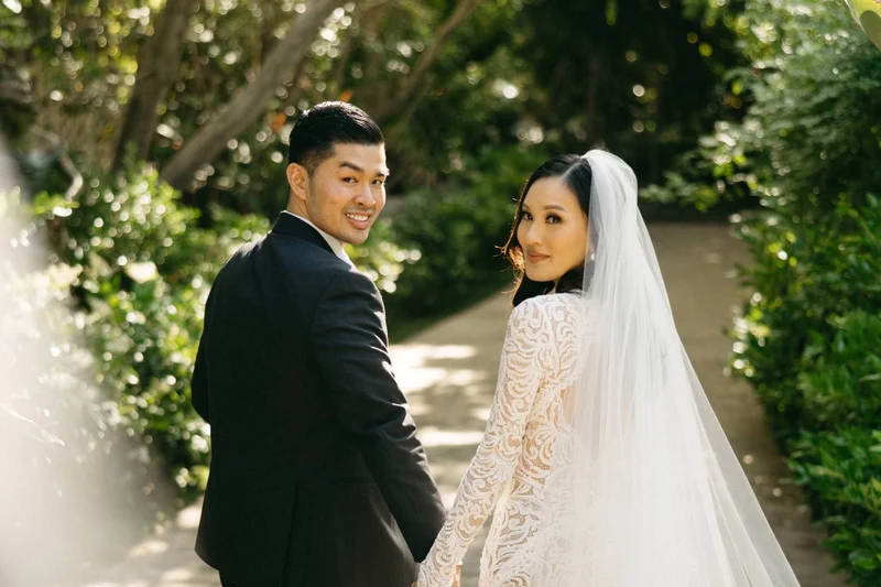 Khoa Photography bride and groom looking back along a garden path