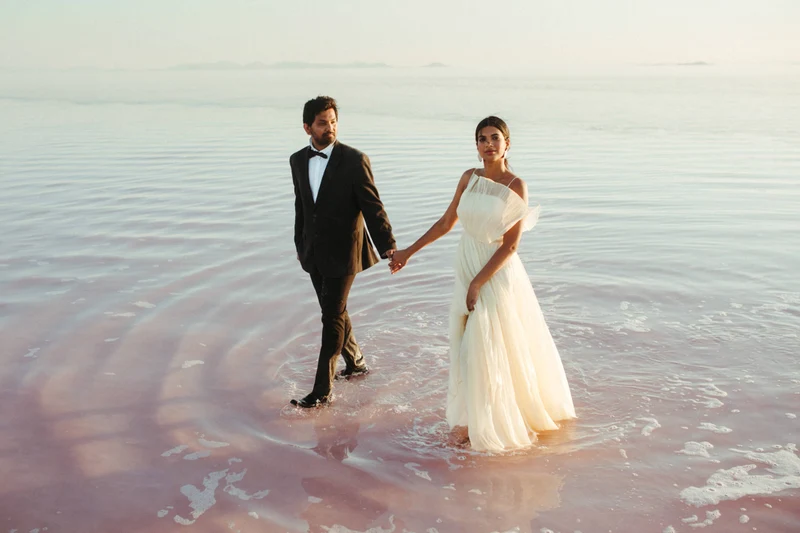 Khoa Photography couple walking hand in hand through shallow water at dusk