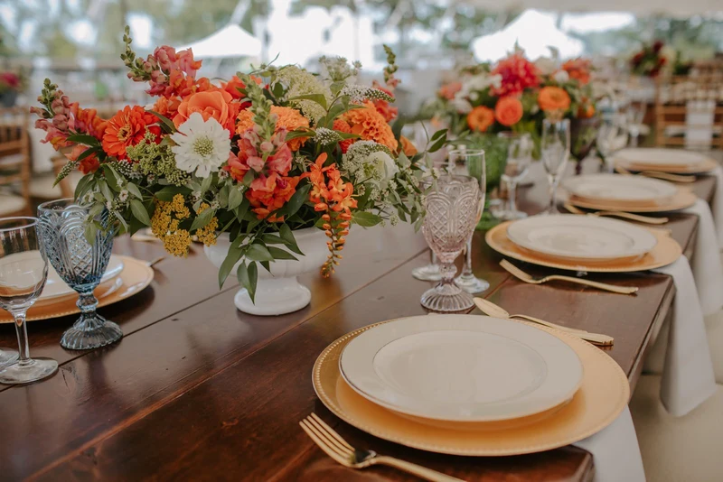 Folls' Flowers centerpiece on a wooden reception table in a tent