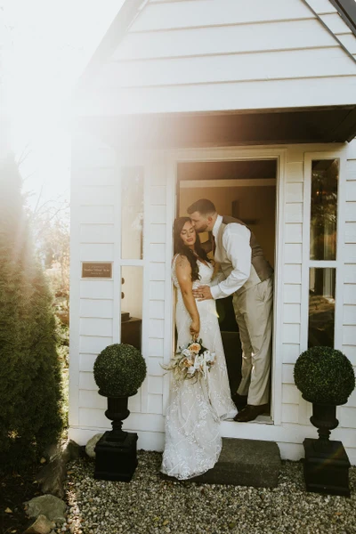 Addie Fath Photography couple in the doorway of a white cottage with topiaries