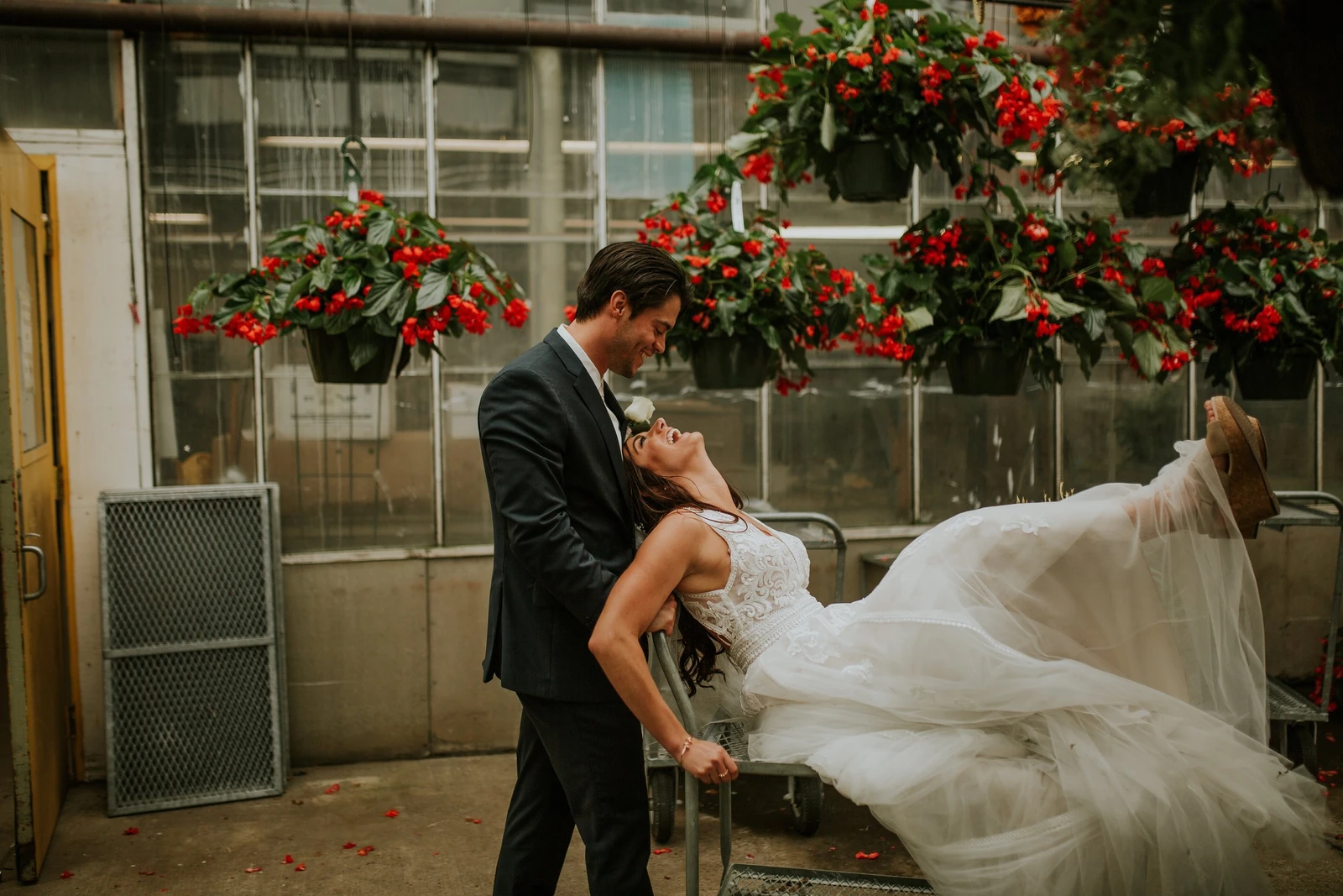 Addie Fath Photography groom dipping the bride outside a greenhouse hung with red flowers