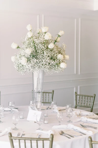 Rose's Bouquets tall centerpiece of white roses and baby's breath on a reception table