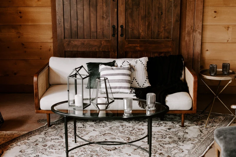 She Rents Vintage lounge with a cane sofa, glass coffee table and patterned rug in front of barn doors