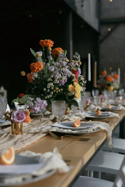 She Rents Vintage reception table with a gauze runner, pressed glass goblets and bright flowers