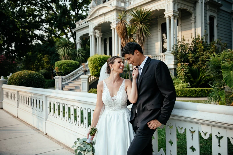 LEAF Wedding Photography bride and groom beside a white fence in front of a Victorian house