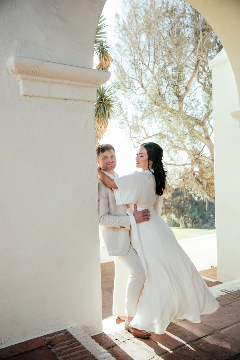 LEAF Wedding Photography couple in white beside a whitewashed archway