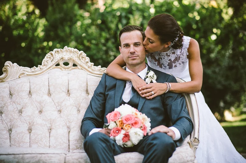LEAF Wedding Photography bride kissing the groom on a vintage sofa in a garden