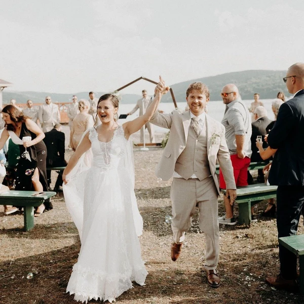 Crown Coordination newlyweds cheering as they walk back up the aisle at an outdoor lakeside ceremony