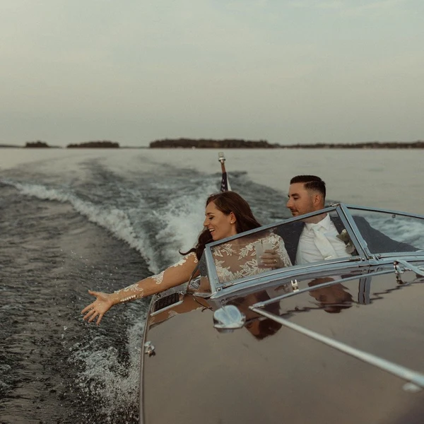 Crown Coordination newlyweds riding in a wooden boat on the water at dusk