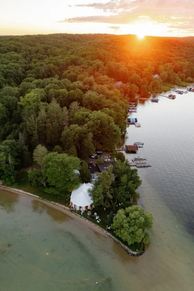 Anna Beth Smith aerial view of a tented wedding on a wooded lakeshore at sunset