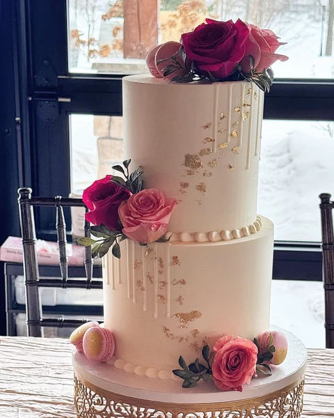 Sugar Blossom Cake Shop two-tier wedding cake with gold leaf, a white drip, roses and macarons