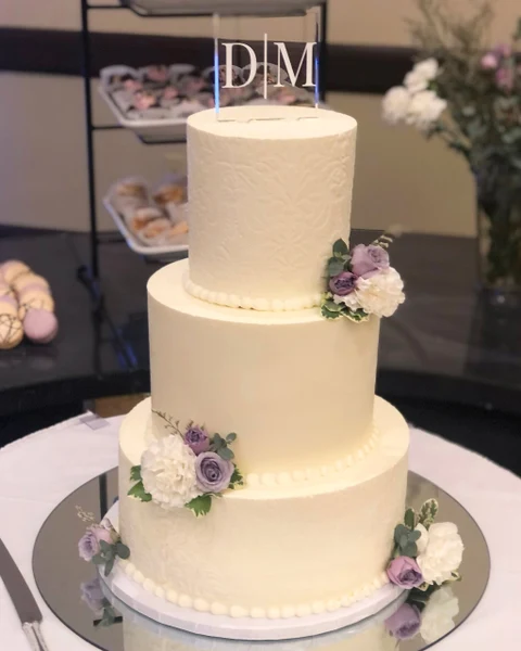Sugar Blossom Cake Shop three-tier buttercream wedding cake with lavender and white flowers