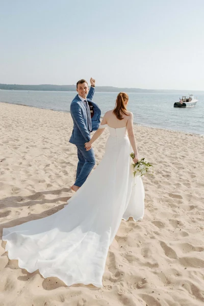 Michael Murphy IV Photography bride and groom walking a sandy beach with a boat offshore