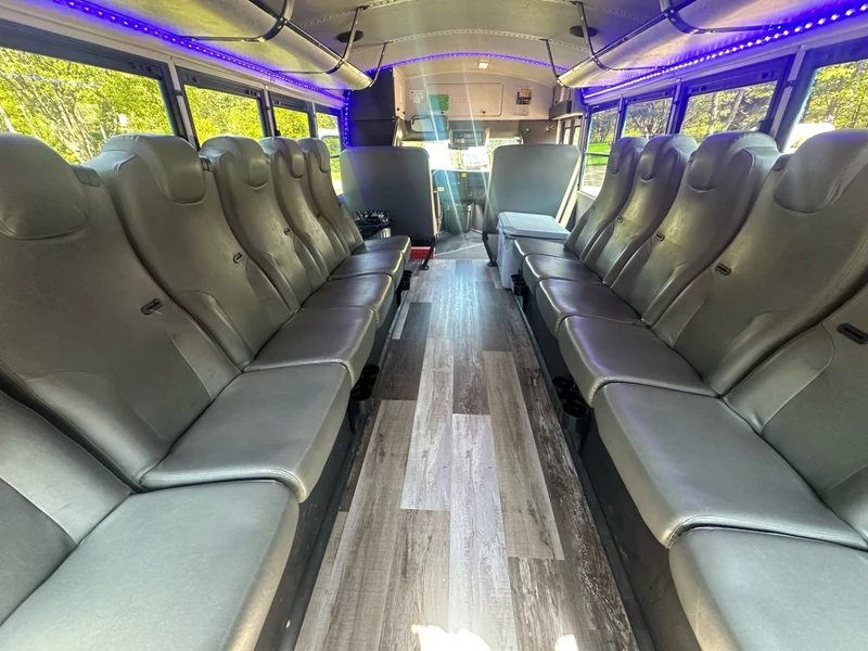The Magic Shuttle Bus interior with perimeter seating, a wood-look floor and LED lighting