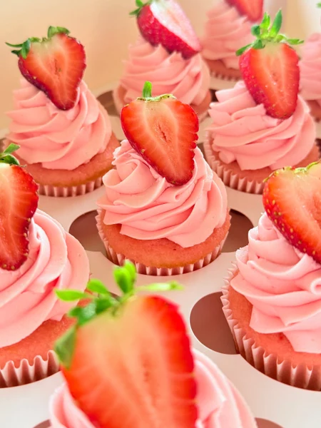 Butter & Batter Bakery strawberry cupcakes with pink frosting and fresh strawberry halves