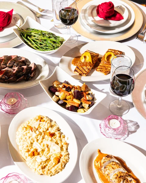 Madeline's Catering formal dining table with plated entrees, asparagus, red wine and pink candles