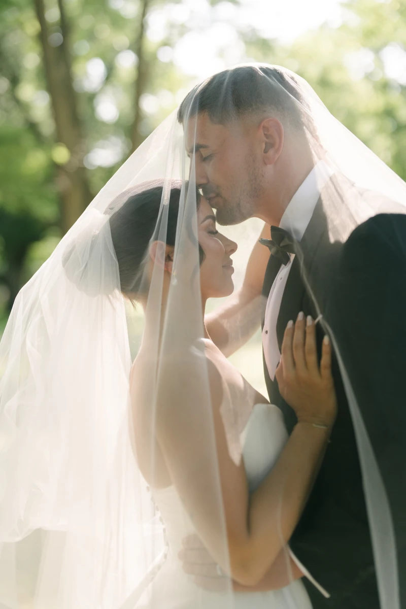 Eliza Jane Events couple embracing under a veil among sunlit trees