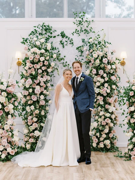 Conradie Event Design bride and groom in front of a tall pink and white floral ceremony arch