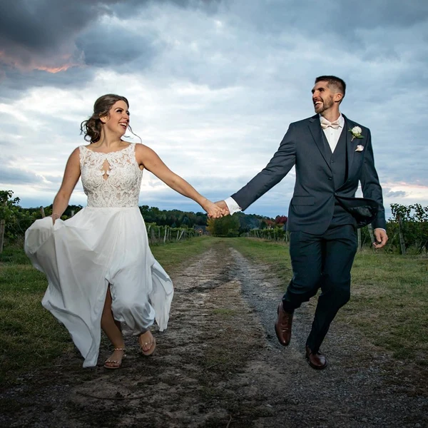 Jeffrey Foote Photography bride and groom running hand in hand down a country lane under a dramatic sky