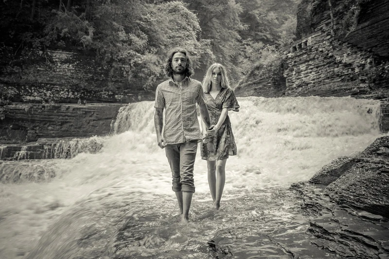 Jeffrey Foote Photography black and white portrait of a couple wading below a waterfall