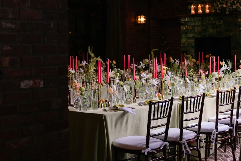 Wilder Gardens + Flowers long reception table with bud vases of spring flowers and tall bright taper candles