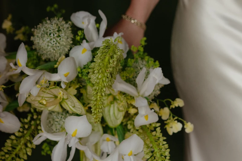 Wilder Gardens + Flowers white and green bridal bouquet held beside a wedding gown