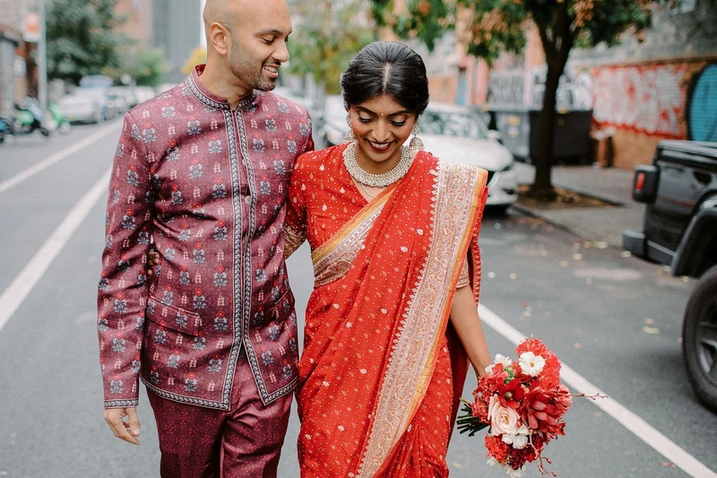Wilder Gardens + Flowers red and white bouquet carried by a couple in wedding attire on a city street