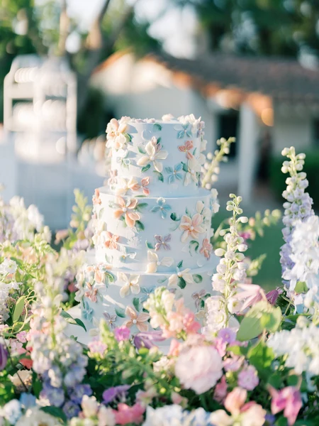 LILA Cake Shop three-tier blue wedding cake with piped buttercream flowers in a garden