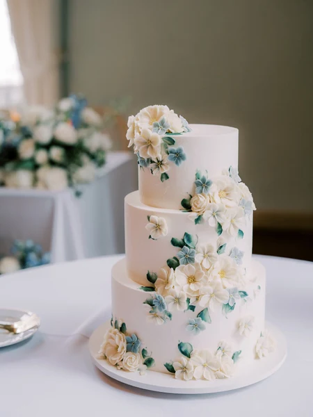 LILA Cake Shop three-tier white wedding cake with blue and ivory buttercream flowers