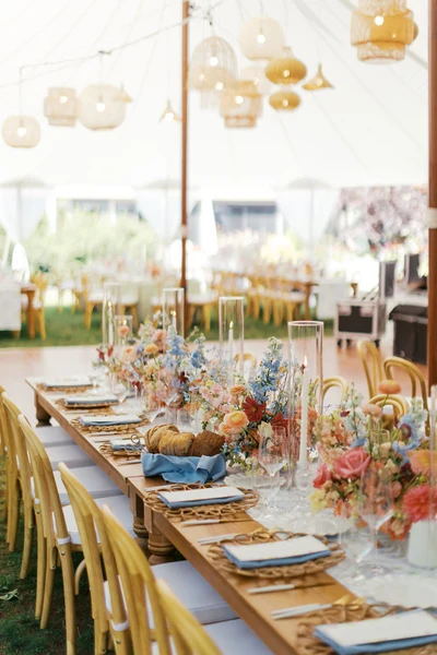 Fox & Fern Events tented reception table set with colorful flowers under woven lanterns