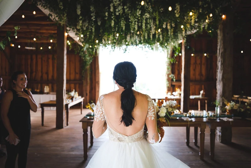 Fox & Fern Events bride entering a barn reception under a hanging floral installation