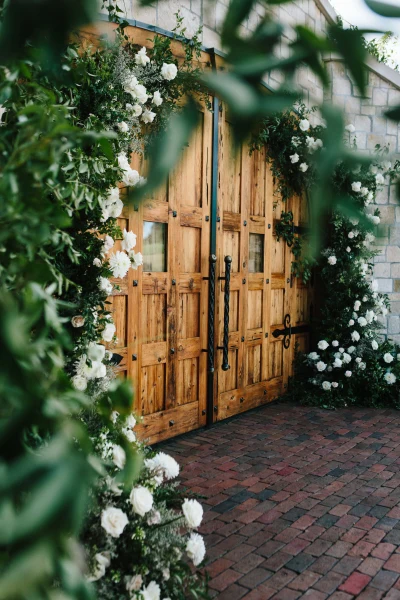Fox & Fern Events wooden doors framed with white flowers and greenery