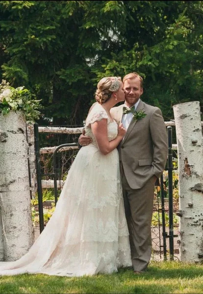 On-Site Bridal bride with a low updo and hairpiece embracing the groom in a garden