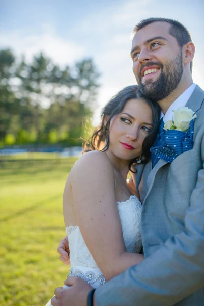 On-Site Bridal bride with dark curls and a red lip leaning on the groom outdoors