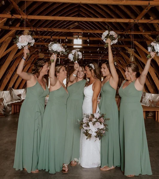 Styles by Lauren bride and bridesmaids with styled hair raising bouquets in a barn